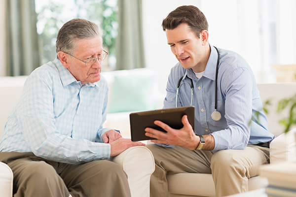 Caucasian doctor and patient using digital tablet at home
