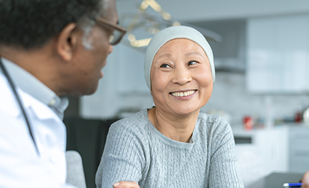 A Korean woman with cancer is meeting with her doctor. Chemotherapy treatment is going well. The patient is smiling at her doctor as he shares with her positive news.