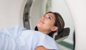 Patient lying down getting a CAT scan at the hospital - healthcare and medicine concepts
