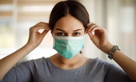 Portrait of young woman putting on a protective mask