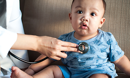 A pediatrician is examining a child with a stethoscope in a clinic