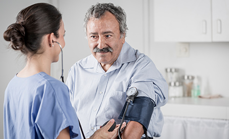 Nurse checking senior man's blood pressure